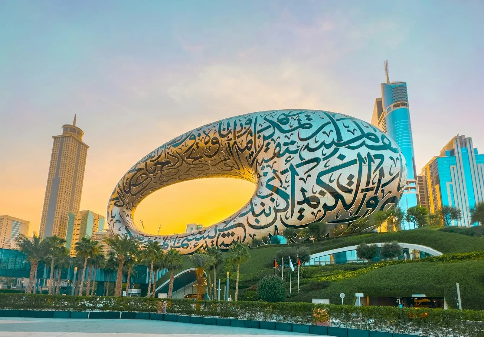 The Museum of the Future in Dubai at golden hour, its steel ring covered in Arabic calligraphy, with the towers of Sheikh Zayed Road behind